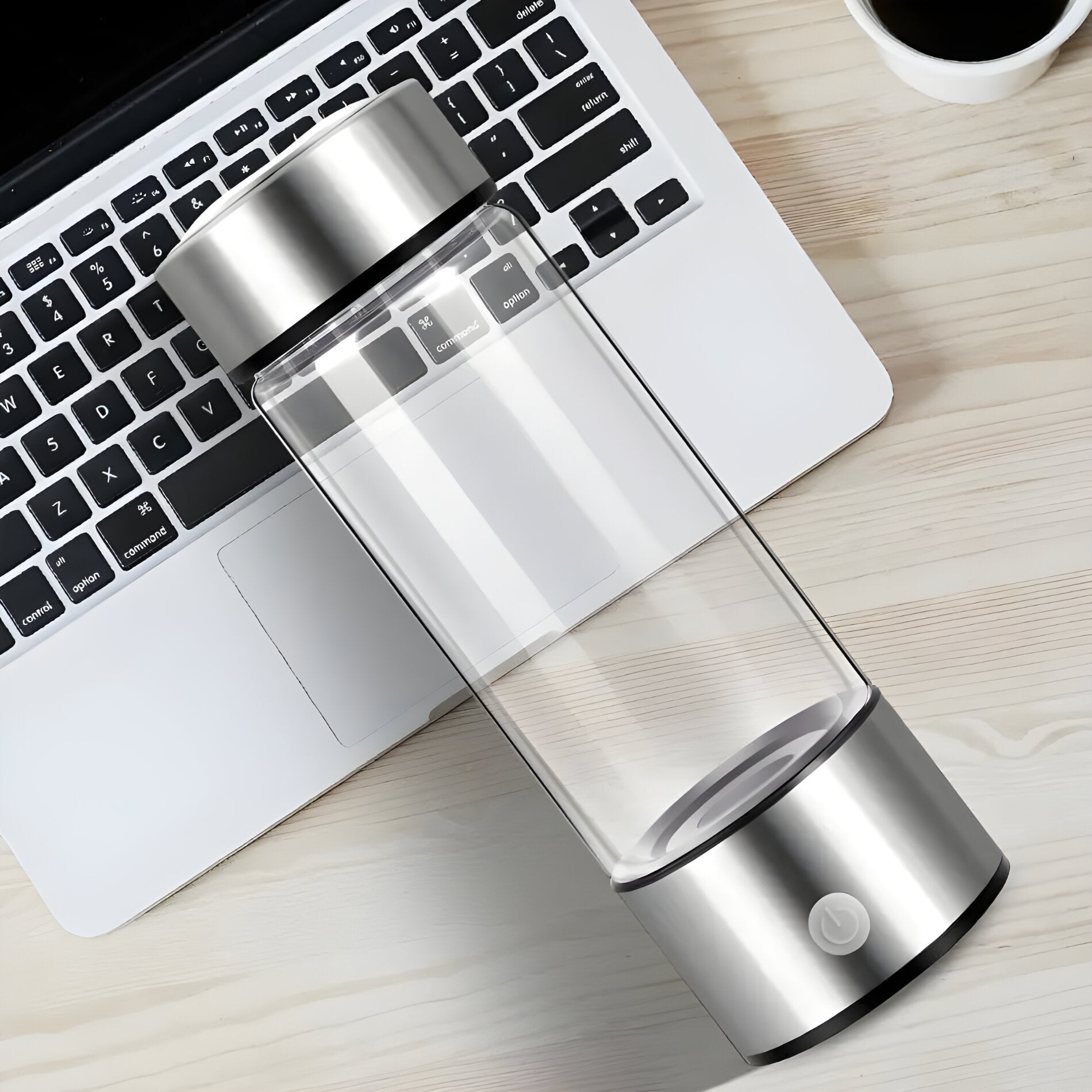 Hydrogen water bottle sitting next to an open laptop and a cup of coffee on a wooden desk, symbolizing a healthy work-life balance.