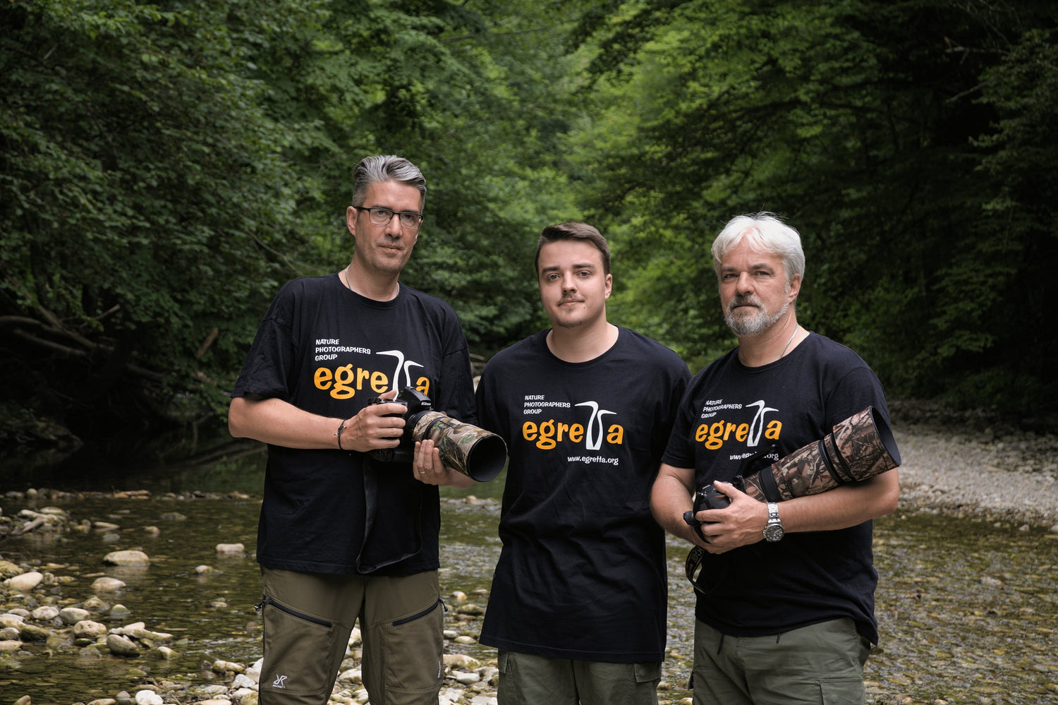 A team photo of the Egretta members in the forest next to a stream. Professional photographers group, high-tech camera.